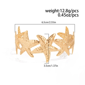 Macro shot of gold-finished starfish bangle featuring a detailed hammered metal texture
