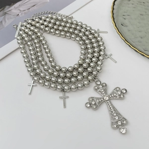 Détail du collier de perles multicouche avec un pendentif en forme de croix serti de cristaux