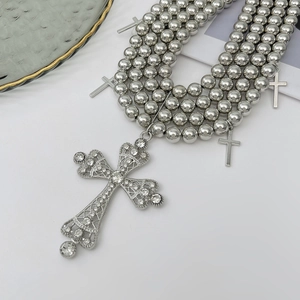 Détail d'un collier de perles argentées à plusieurs rangs avec croix gothique en strass