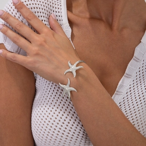 Detailed view of silver starfish open cuff bracelet with textured marine design on wrist