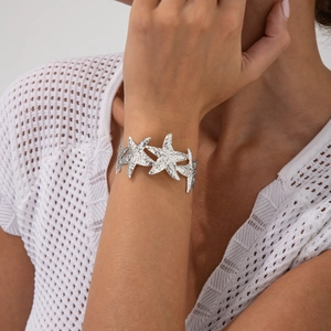 Detailed close-up of a silver starfish cuff bracelet with textured metallic surface
