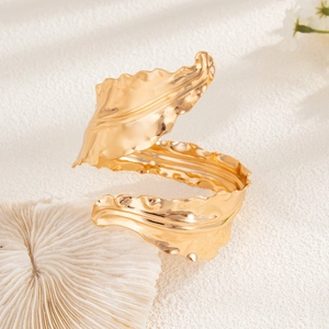 Detail shot of golden metal leaf cuff featuring intricate leaf veins and polished finish
