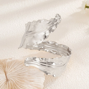 Macro detail of silver leaf arm cuff with hammered texture on white coral stand