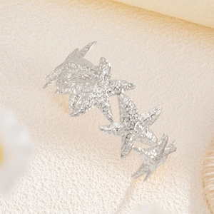 Macro detail of silver starfish hair clip with realistic textures on sandy background