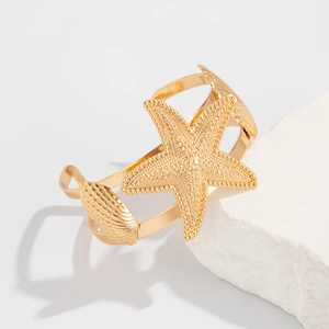 Detail of gold starfish and seashell textures on an irregular metal open cuff bracelet