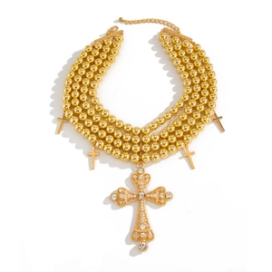 Collier multicouche de perles dorées avec pendentifs croix en strass sur fond blanc