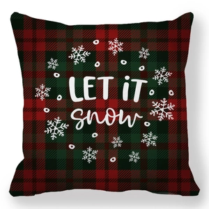 Detail of red and green tartan Christmas pillow cover featuring white Let It Snow text