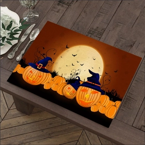 Close-up of Halloween linen placemat with pumpkin and wizard hat on a dark wood table
