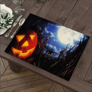 Detail of Halloween linen placemat featuring glowing pumpkin and haunted house print