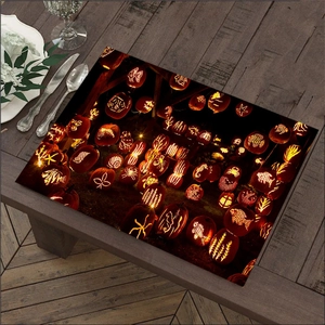 Detailed view of Halloween pumpkin linen placemat on a rustic wood dining table