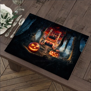 Close-up of Halloween linen placemat with glowing pumpkin print on dark wood table