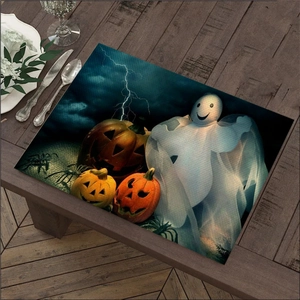 Detail of Halloween linen placemat featuring glowing pumpkin and ghost prints on wood