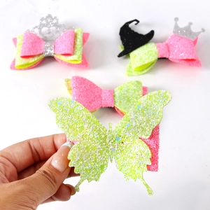 Close-up of pink and green glitter hair clips with crown and witch hat charms