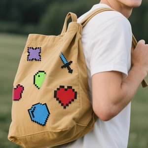 Dettaglio di toppe pixel art su borsa in tela con icone di spada e cuore stile Minecraft