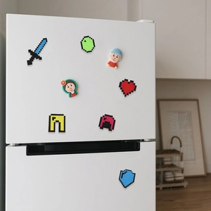 Dettagli di adesivi in feltro in stile pixel e icone su una superficie bianca del frigo