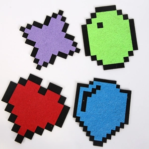 Vista macro di 4 toppe in feltro pixel art con colori vivaci e stile di gioco retrò