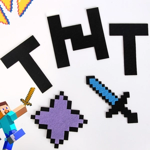 Dettaglio macro di adesivi murali in feltro pixel con lettere TNT e una spada pixel blu