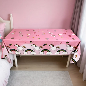 Detail of pink unicorn party tablecloth with rainbow and donut prints for birthdays