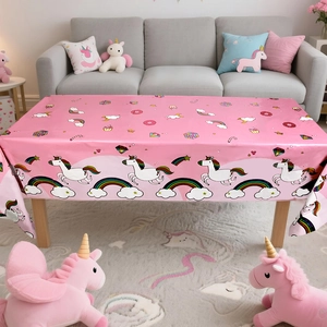 Detail of pink unicorn party tablecloth with rainbow prints on a rectangular table