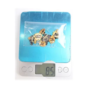 Close-up of lightweight acrylic Happy New Year earrings on a digital scale weighing 8.5g