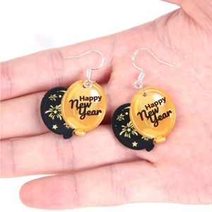 Detail of acrylic Happy New Year balloon earrings featuring golden fireworks pattern