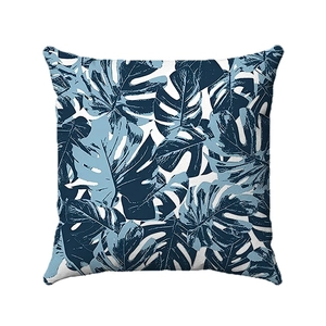 Detail of soft monstera leaf print on blue and white tropical throw pillow cover
