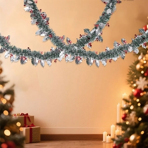 Detail of dark green Christmas garland with silver holly leaves and red berries on a wall
