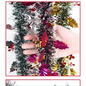 Detail view of green Christmas tinsel with red berries and shiny metallic leaves