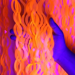 Dettaglio della tenda a frange ondulate arancione neon con reazione alla luce UV