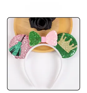 Detail of sequined ears headband with pink bow, broom and crown motifs for party decor
