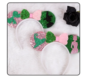 Detail of sequined witch ears headband with pink and green bows on plush background