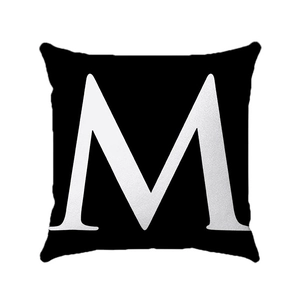 Macro shot of minimalist black square pillow cover with white printed letter M and fabric texture