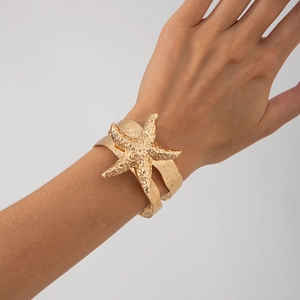 Detail eines breiten Gold-Armreifs mit strukturierter Oberfläche und Seestern-Motiv