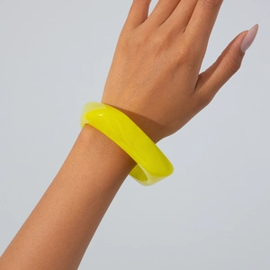 Close-up of a chunky translucent yellow acrylic bangle with a polished minimalist finish