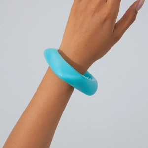 Detail shot of chunky bright blue irregular acrylic bangle on model's wrist