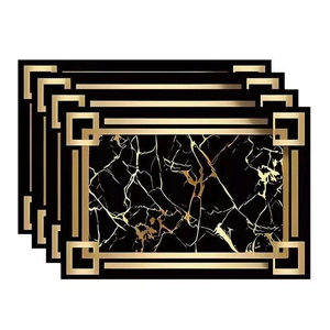 Detail of four black and gold marble pattern placemats with geometric borders