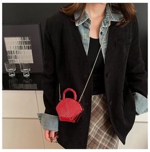 Mini borsa rossa testurizzata con tracolla a catena dorata indossata da modella