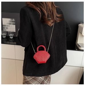 Dettaglio della mini borsa rossa con trama a rombi e tracolla a catena dorata