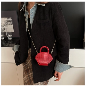 Dettaglio mini borsa in acrilico rosso con forma geometrica e catena dorata