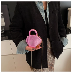 Dettaglio mini borsa con strass rosa e catena d'oro indossata su giacca nera chic