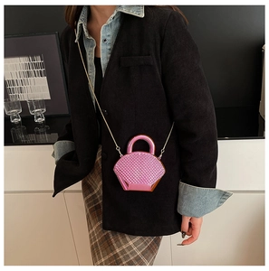 Dettaglio di una mini borsa a tracolla rosa acceso con catena dorata e trama a rombi