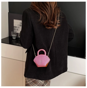 Dettaglio della mini borsa con strass rosa con manico rotondo e tracolla a catena dorata