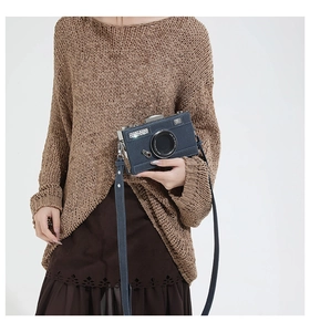 Close-up of a vintage navy blue camera-shaped crossbody bag worn over the shoulder