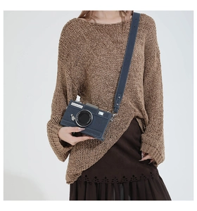 Close-up of retro camera-shaped crossbody bag in navy blue leather worn by a model