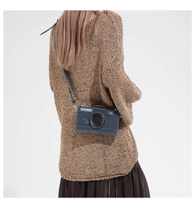 Detail of greyish-blue camera bag with leather texture and white stitching details