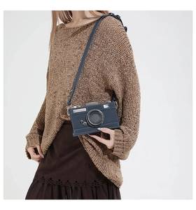 Detail of creative camera-shaped crossbody bag worn with autumn knitwear and skirt