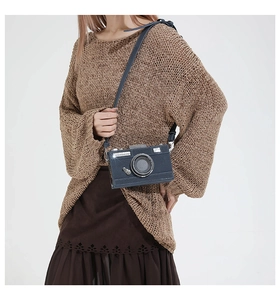 Detail of a vintage camera-style crossbody bag worn with a warm autumn knit sweater