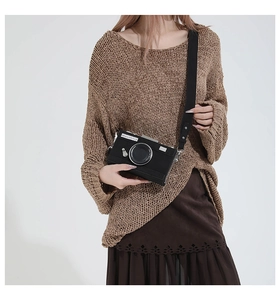 Detail of a vintage camera-shaped crossbody bag featuring silver metallic lens accents