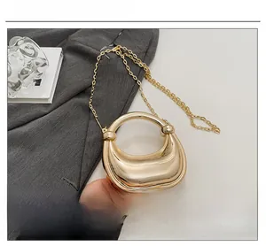 Detailed view of glossy gold mirror crescent handbag with sleek metal chain strap