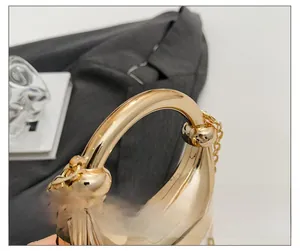 Close-up of golden metallic moon-shaped handbag with polished handle and chain strap